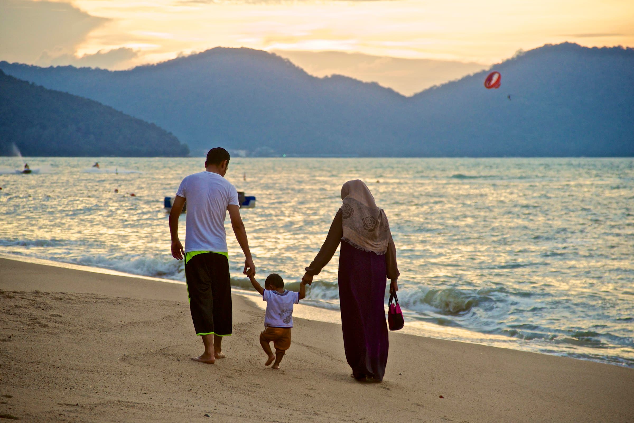 Keluarga berjalan bergandengan di tepi pantai